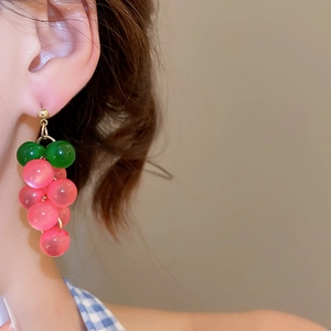 Detail of model wearing translucent pink and green resin grape tassel drop earrings