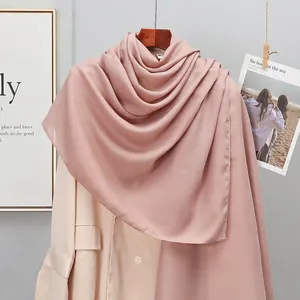 Detail of soft lotus pink linen scarf draped over a beige blazer in a stylish setting