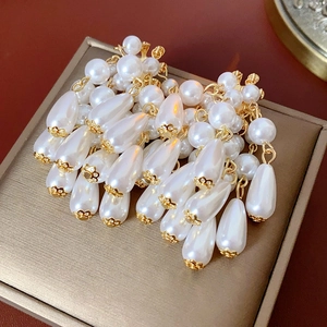 Close-up of white teardrop pearl tassel earrings with gold hardware in a gift box