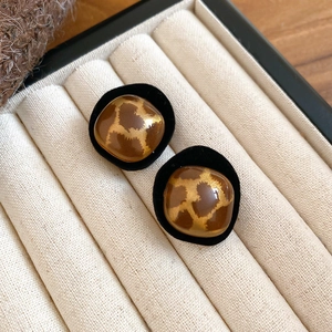 Detailed close-up of vintage brown leopard print stud earrings with black velvet trim
