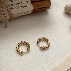 Polished gold twisted rope hoop earrings on vintage newspaper and wooden background