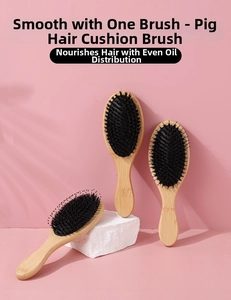 Detail view of boar bristle hairbrushes with bamboo handles on a soft pink background