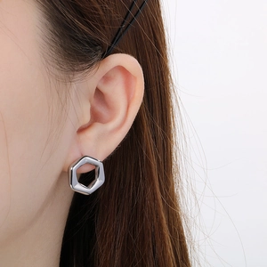 Close-up of a silver-toned hexagonal earring worn on ear with high-quality metal finish