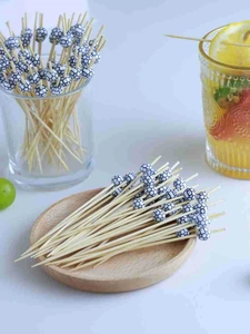 Close-up of bamboo cocktail picks with soccer ball beads on a wooden tray