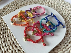 Detailansicht bunter geflochtener Armbänder mit goldenen Buchstabenanhängern
