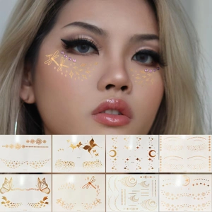 Metallic gold face tattoos with stars, moons, and butterflies set on female model face
