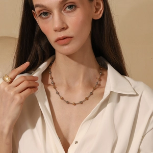Minimalist gold and silver beaded necklace shown on model wearing white shirt