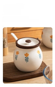 Detail of ceramic seasoning jar with yellow tulip pattern, lid and spoon, macro view