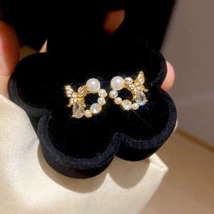 Macro detail of gold butterfly earrings with pearls and zircon in a black velvet box