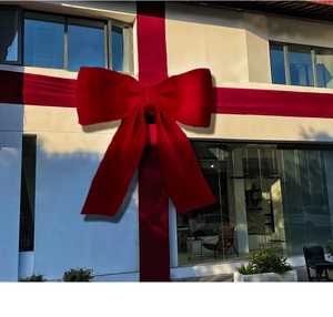 Macro detail of oversized red velvet Christmas bow decoration on building facade