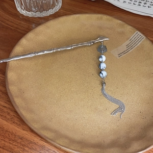 Detail of silver bamboo-shaped hair pin with light blue flower and ink pattern beads