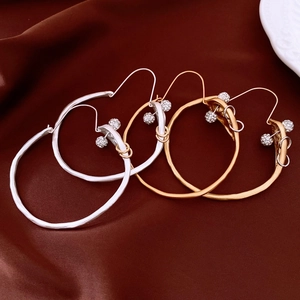 Detail showing textured gold and silver hoop earrings on a dark brown silk background