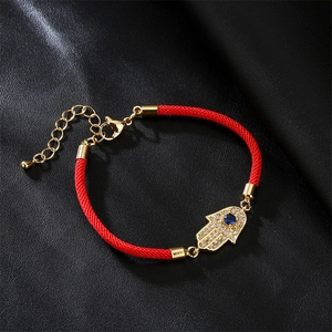 Detail of red Milan cord bracelet with gold Hamsa hand and blue evil eye charm