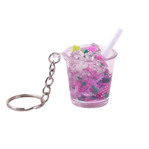 Miniature juice cup keychain with purple liquid, strawberry and ice cubes on white background
