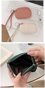 Detail of mini leather coin purses in pink and beige with wrist strap and zipper closure