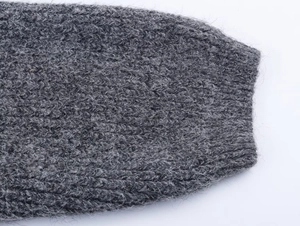 Close-up of dark grey thick knit sweater sleeve with fuzzy texture and ribbed cuffs
