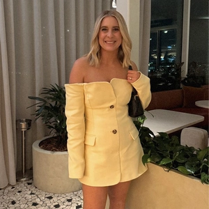 Close-up of yellow off-the-shoulder blazer dress with buttons and pocket details