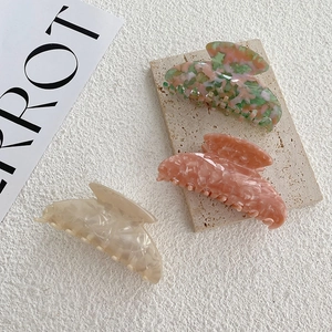 Détail de grandes pinces à cheveux en acétate marbré en rose, corail et blanc ivoire
