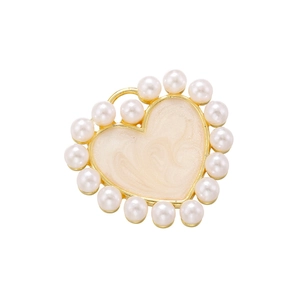 Macro shot of heart-shaped pendant with gold metal frame, white pearls and marble texture