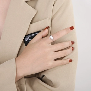 Close-up of a silver heart ring with micro-pave crystals on a model hand with red nails