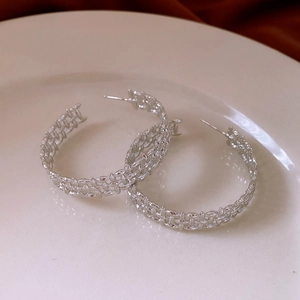Detailed view of silver C-shaped hoop earrings with intricate woven hollow pattern