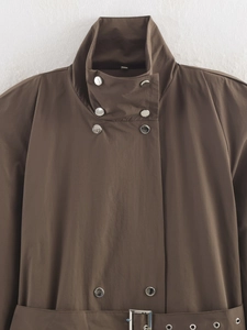 Detailed close-up of brown trench coat with stand collar, snaps and buckled waist belt