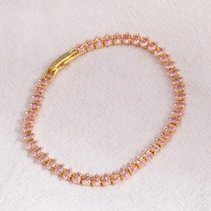 Close-up of pink marquise-cut zircon tennis bracelet with gold finish and jewelry clasp