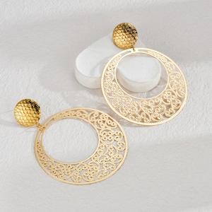 Detail of gold metal earrings with hammered texture and intricate hollow woven pattern