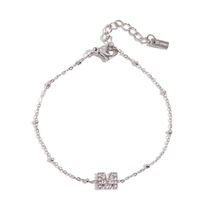 Macro view of silver stainless steel chain bracelet with a zircon encrusted letter M pendant