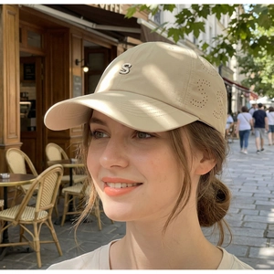 Detail of beige baseball cap with 3D embroidered S logo and laser-cut vents on model