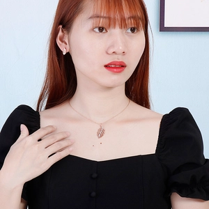 Parure de bijoux feuille en or rose avec collier et boucles d'oreilles sur un modèle