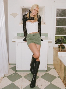 Détail d'une mini-jupe cargo vert olive délavé avec haut en dentelle blanche et bottes