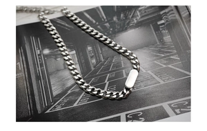 Detailed top view of silver titanium steel Cuban link chain with square pendant on artistic background