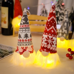Close-up of glowing LED Christmas gnomes with red and grey knitted hats and warm lights