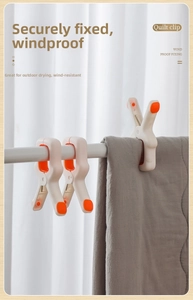 Detail of three heavy duty windproof quilt clips in orange and white fixing a grey blanket