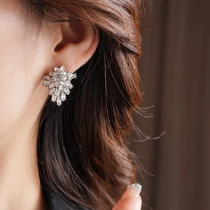 Close-up of sparkling floral silver stud earrings with marquise zircon stones on ear
