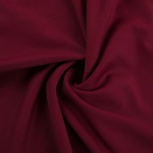 Detailed close-up of wine red evening dress fabric with soft drapes and fine texture
