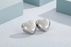 Detail shot of heart-shaped silver earrings on minimalist geometric background