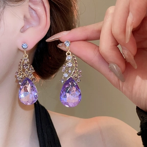Close-up of elegant purple teardrop crystal earrings worn by a model in a luxury style