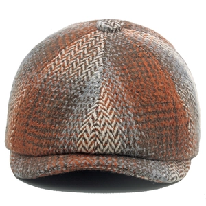 Detail of herringbone and plaid tweed flat cap in warm orange and brown tones