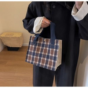 Detail of blue and brown plaid canvas tote bag with snap button closure and sturdy handles