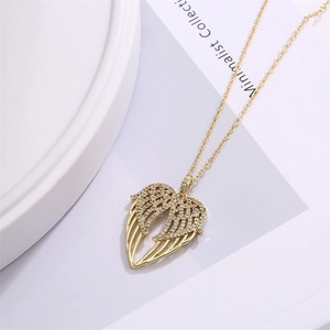Détail du pendentif ailes d'ange plaqué or avec micro-zirconium sur fond blanc épuré