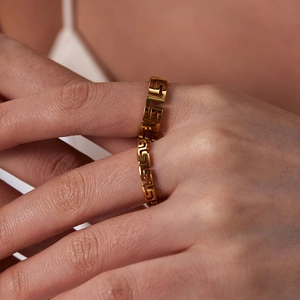 Detailed macro view of a gold-plated stainless steel ring with Greek key cutout patterns