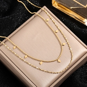 Double-layered gold titanium necklace with geometric diamond pendants on a jewelry box