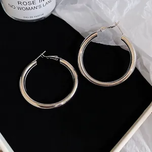 Minimalist silver circular hoop earrings with a high-polished mirror finish on a black tray