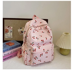 Detailed view of pink corduroy backpack with cherry pattern in a cozy setting