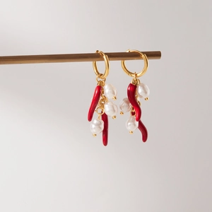 Dettaglio di orecchini a cerchio dorati con ciondoli peperoncino e perle barocche