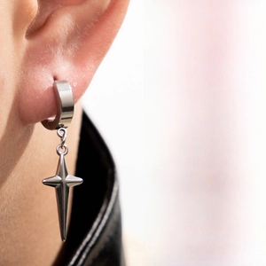 Macro side view of polished stainless steel cross star earring pendant on a model