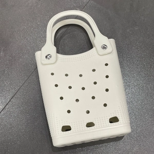 Top view of a white EVA beach tote bag with circular cutouts on gray tile floor