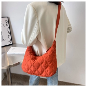Detail of bright orange quilted hobo bag with adjustable strap and diamond stitching